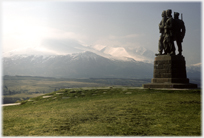 Monument of three men looking across to snow covered mountains.