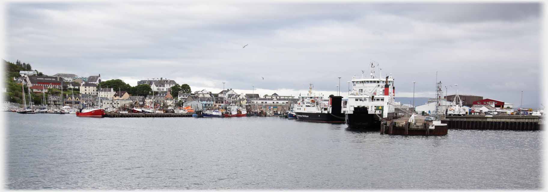 Ships waiting by houses across water.