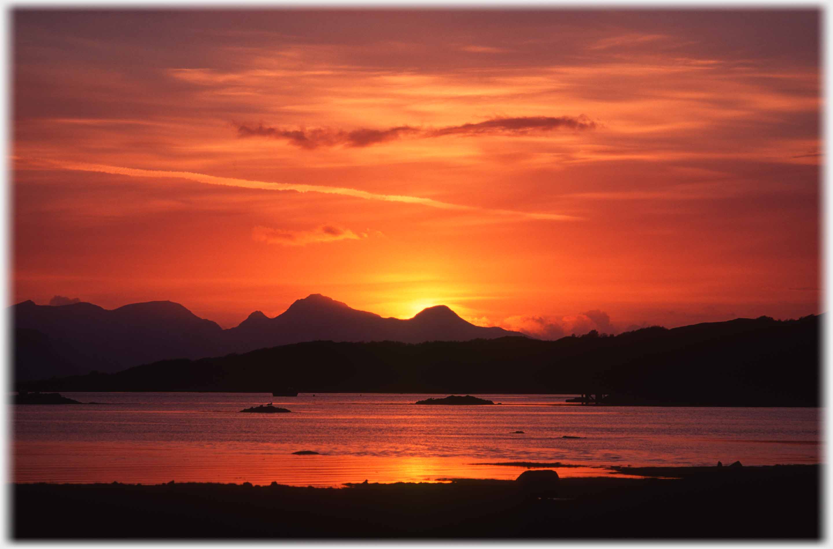 Red sunset stemming from behind mountain range.