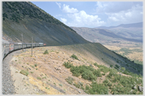 Rail line cutting track high on mountain side.