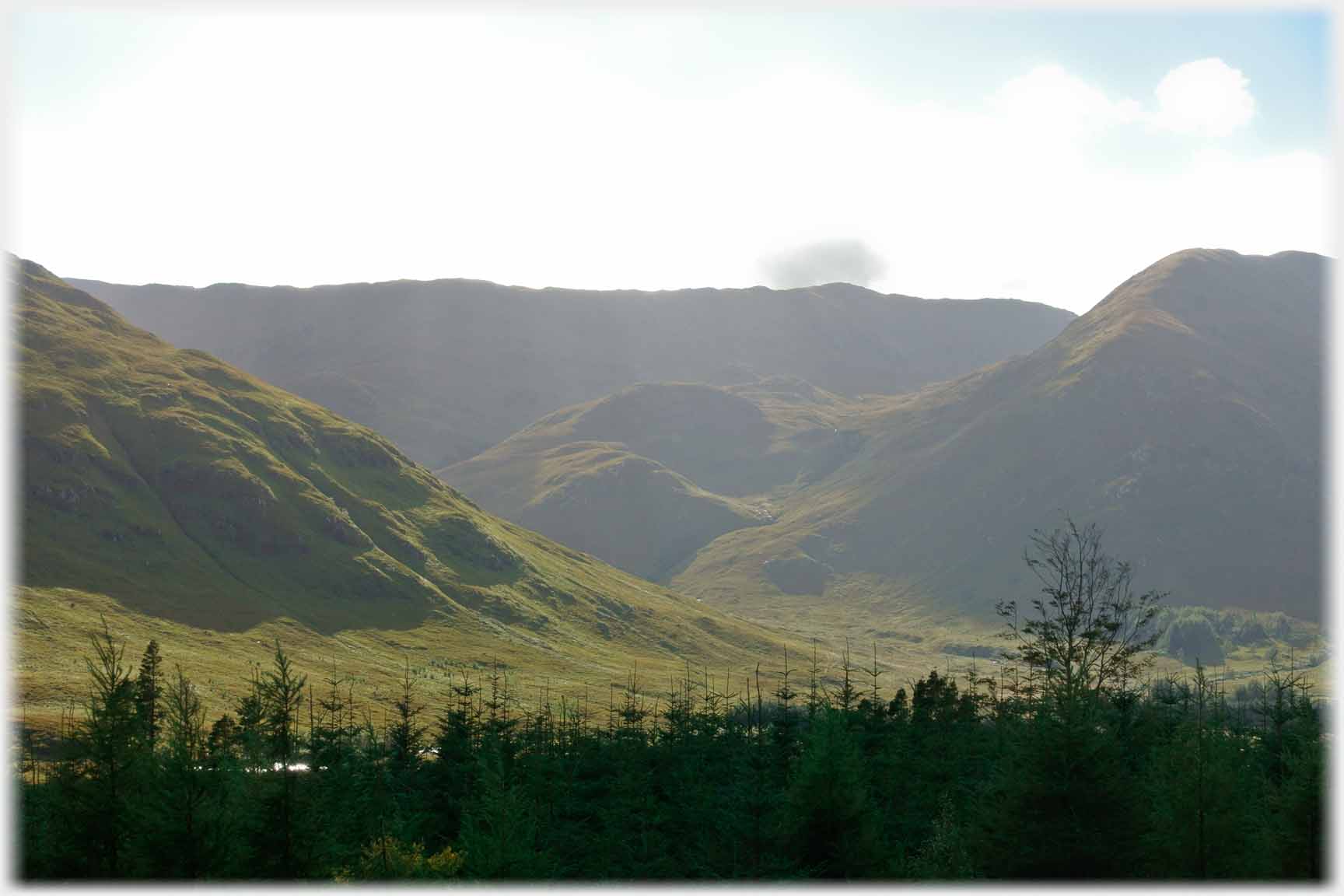 Dark hillocks at valley entrance.