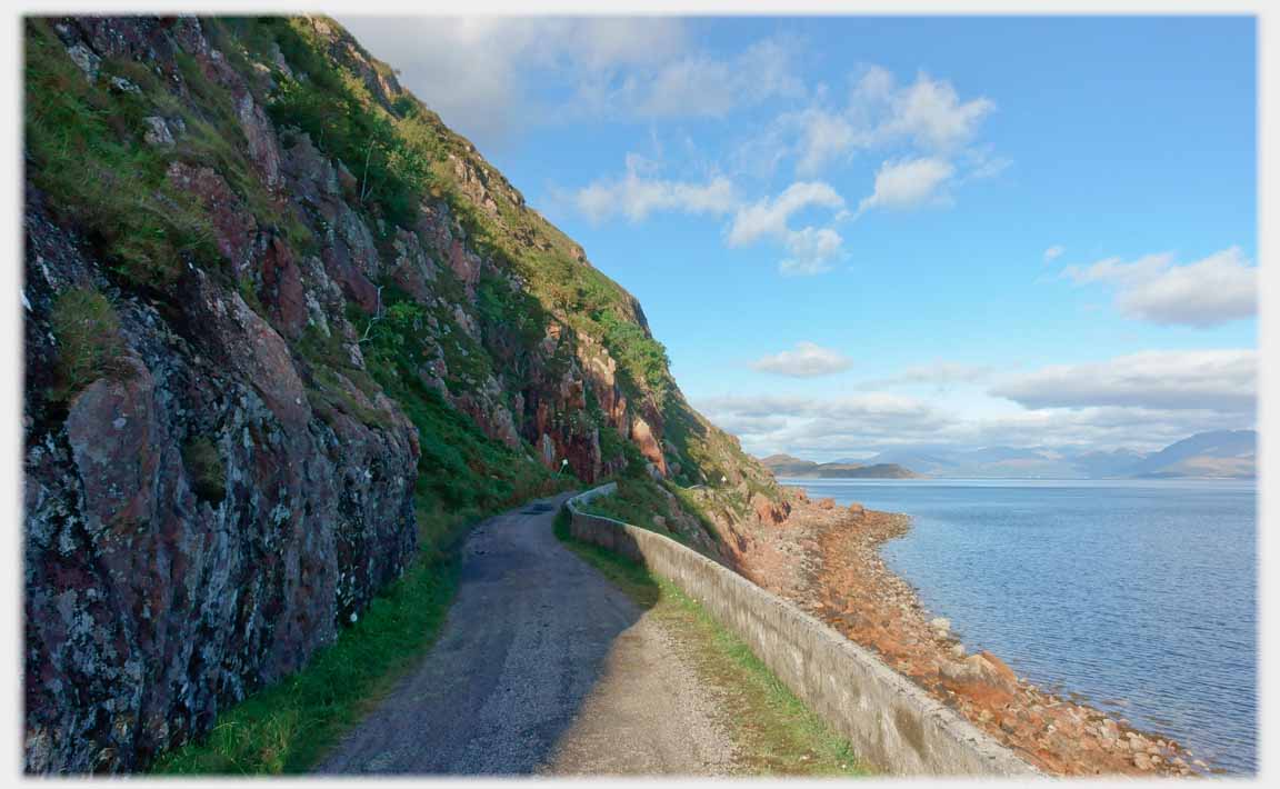 Road under cliff above sea.