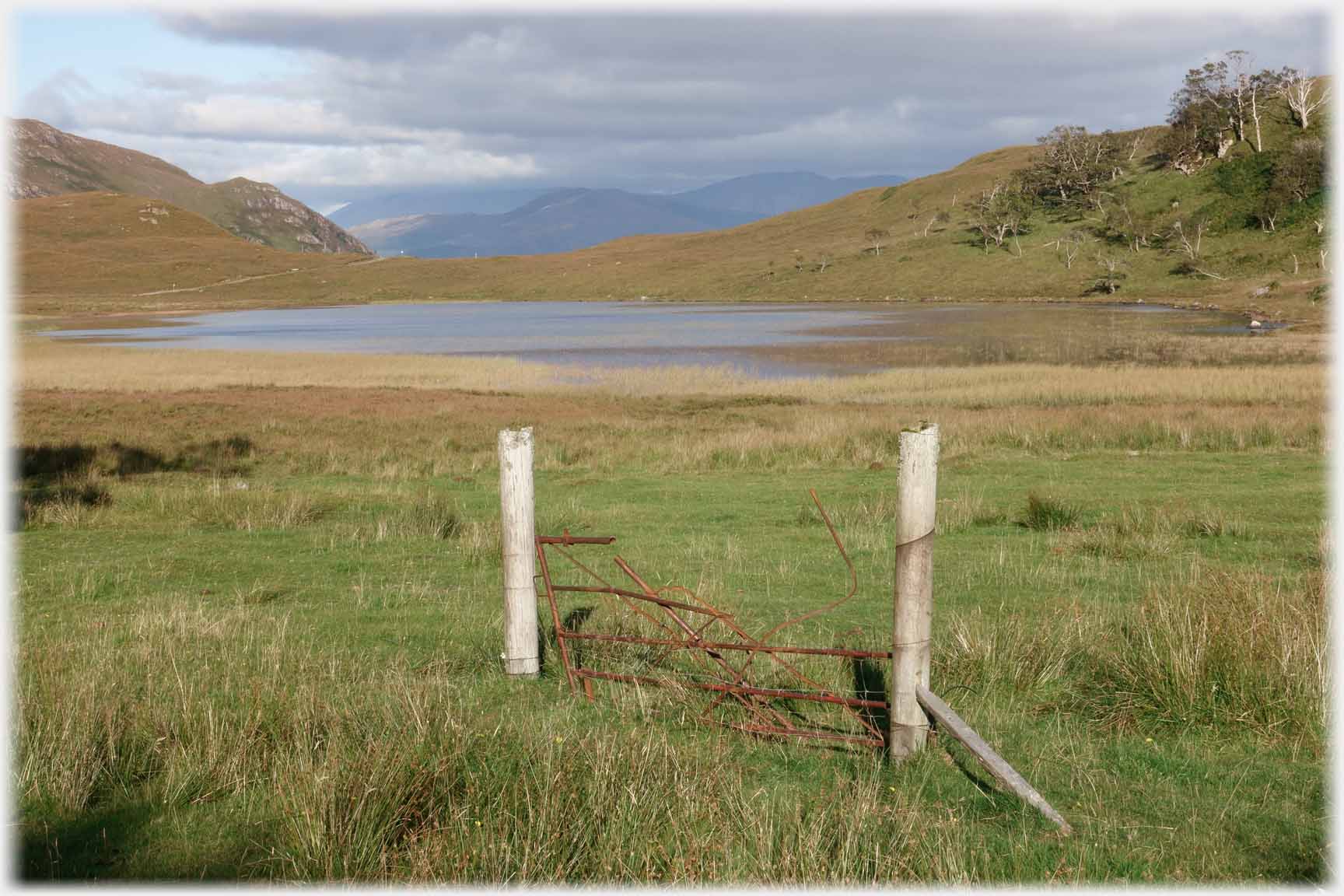 Gate with no fence and lochan beyond.