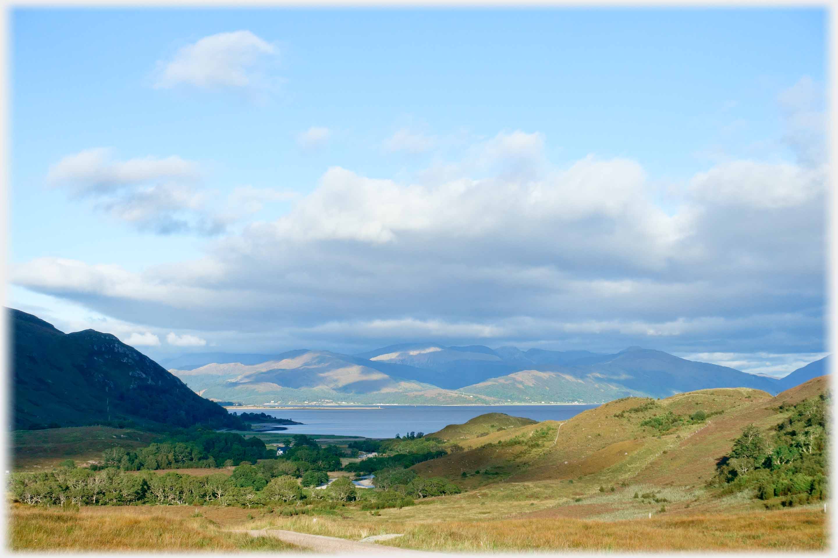 Vista of wide valley leading to sea and hills beyond.