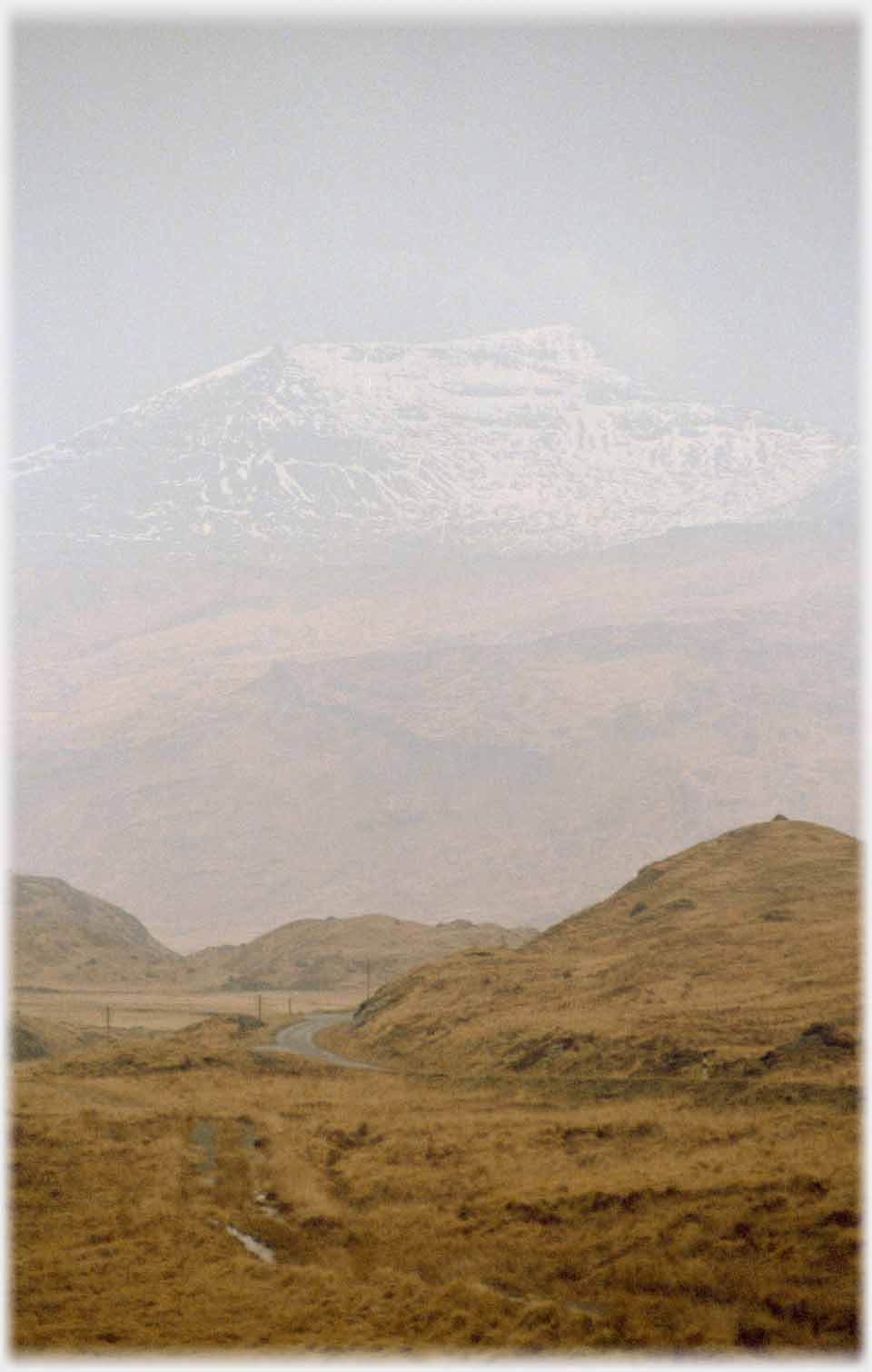 Dim outline of snow sprinkled mountain.