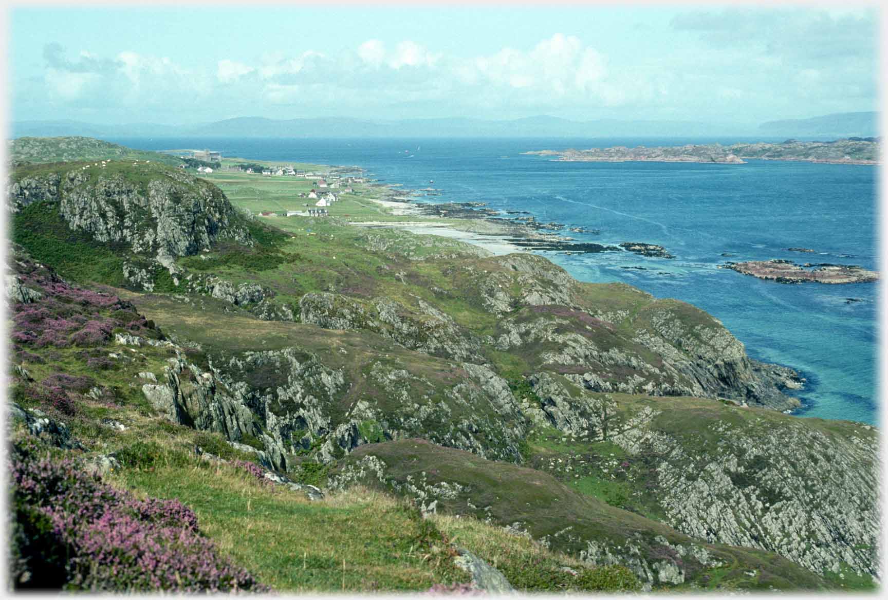 Distant village by sea with background hills.