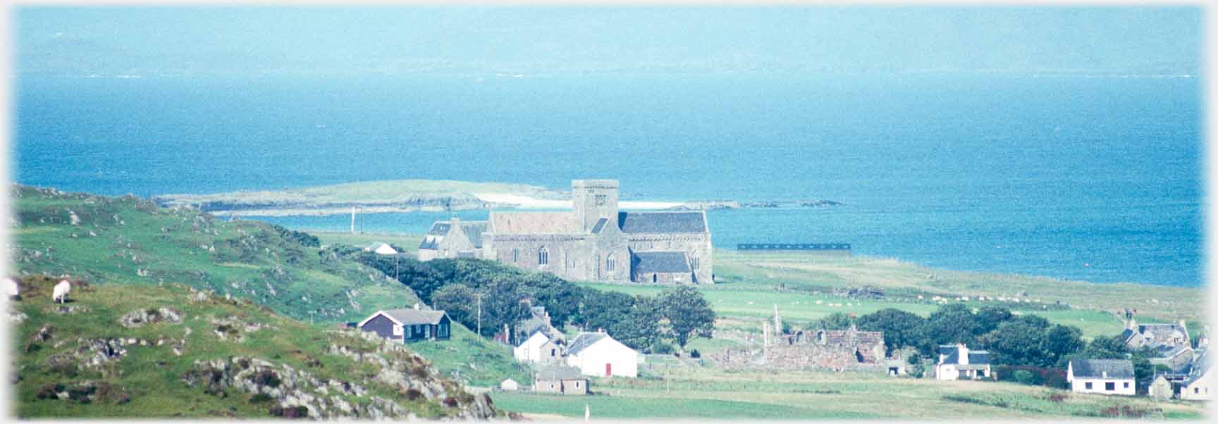 Church with houses in front and sea beyond.