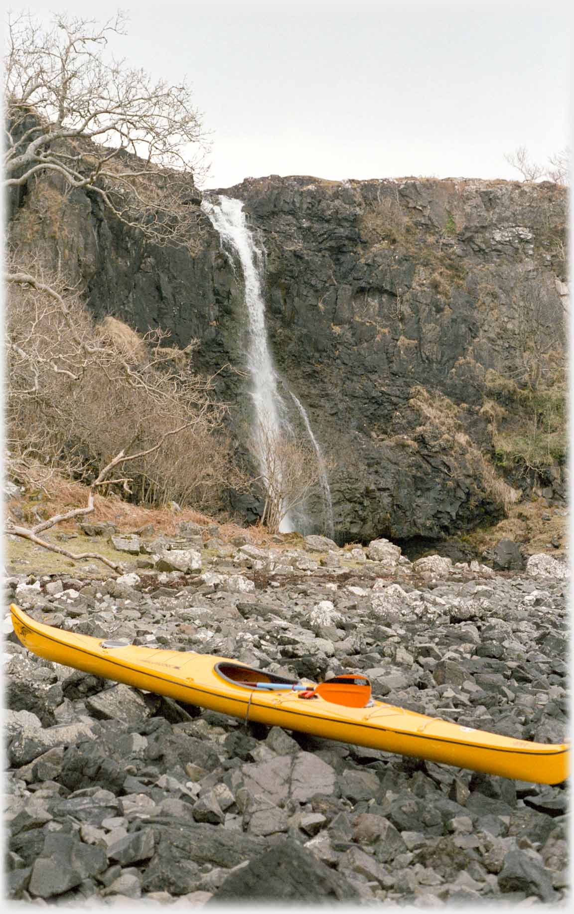 Waterfall with canoe on rocks in front.