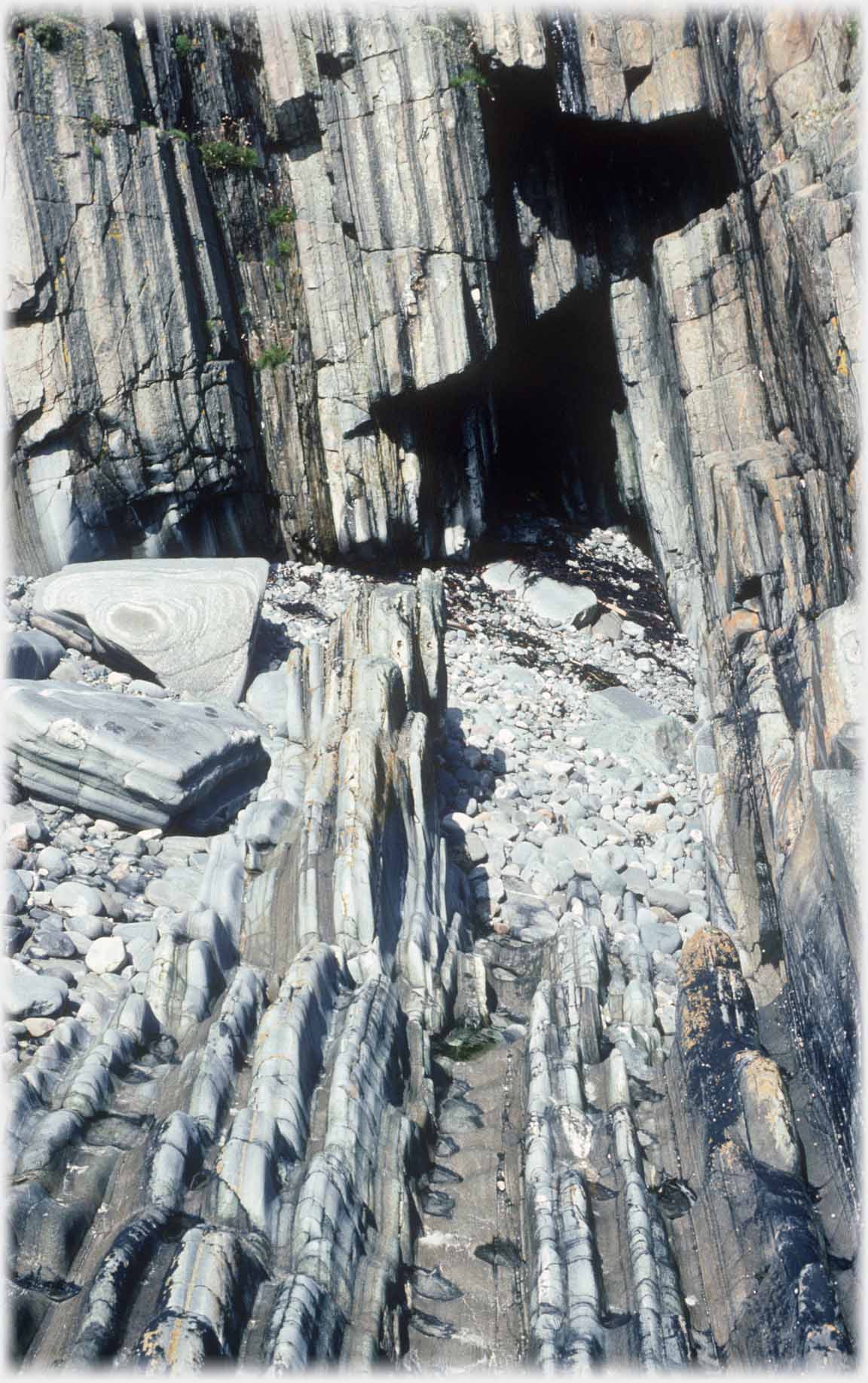 Striking rock formation; like pages of a book with cave.