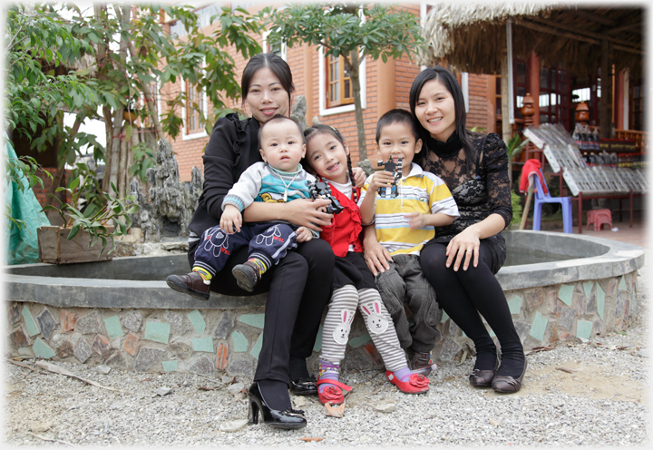 Huyen and Duyen sitting with their children.