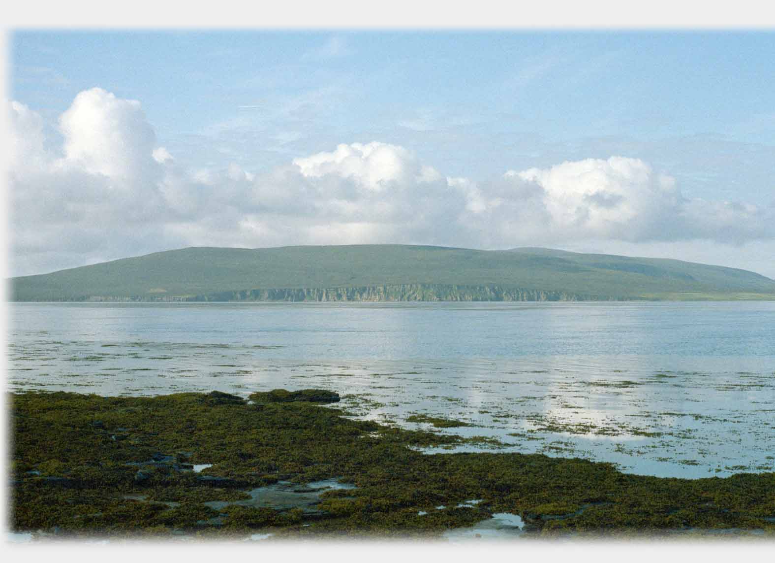 Low hump of island with cliffs along the near seaboard.