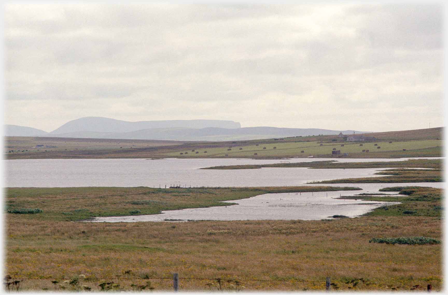 water between fields in foreground, hills in the distance.