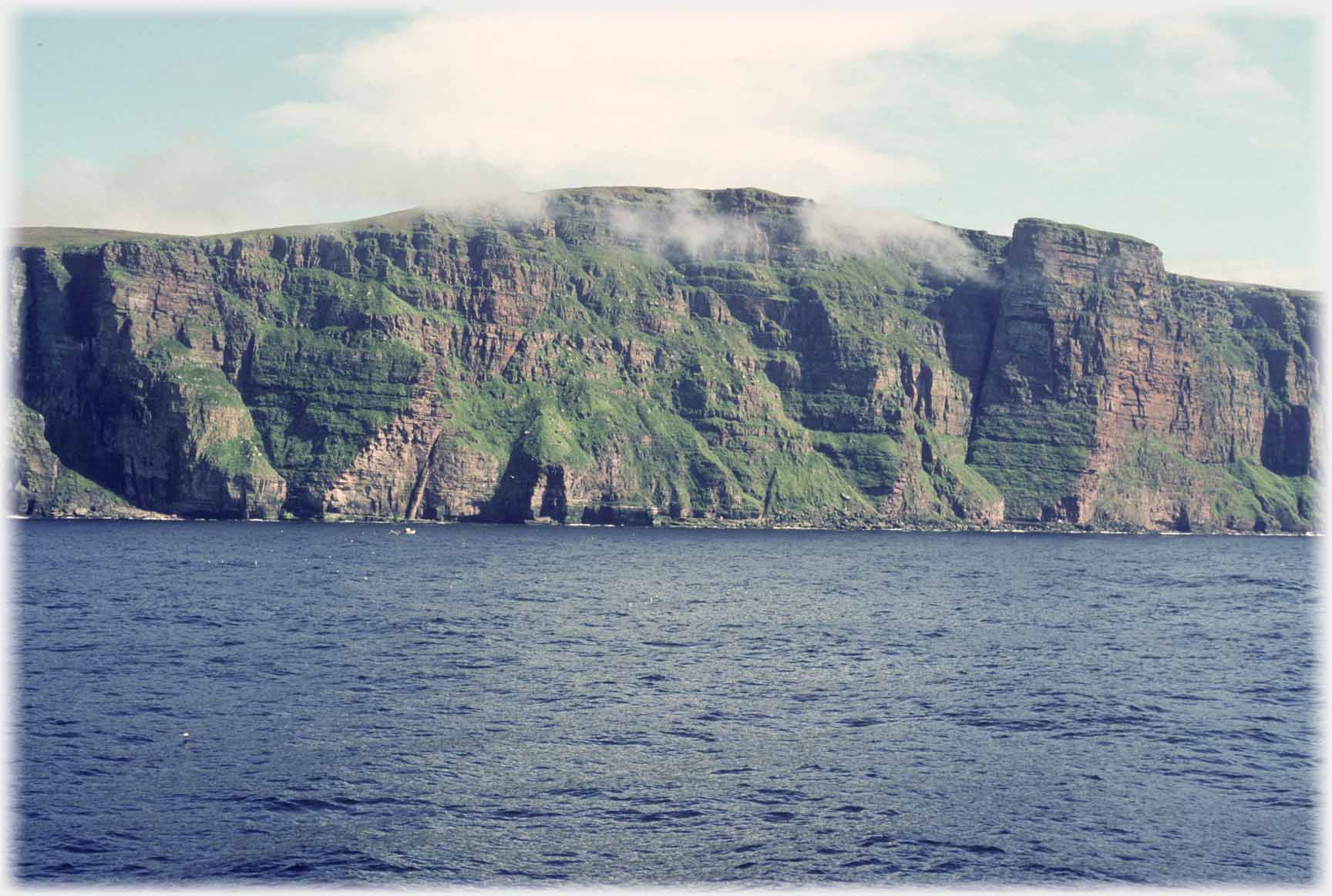 View of St Johns Bastion from further out to sea with whisps of cloud around the cliff tops.