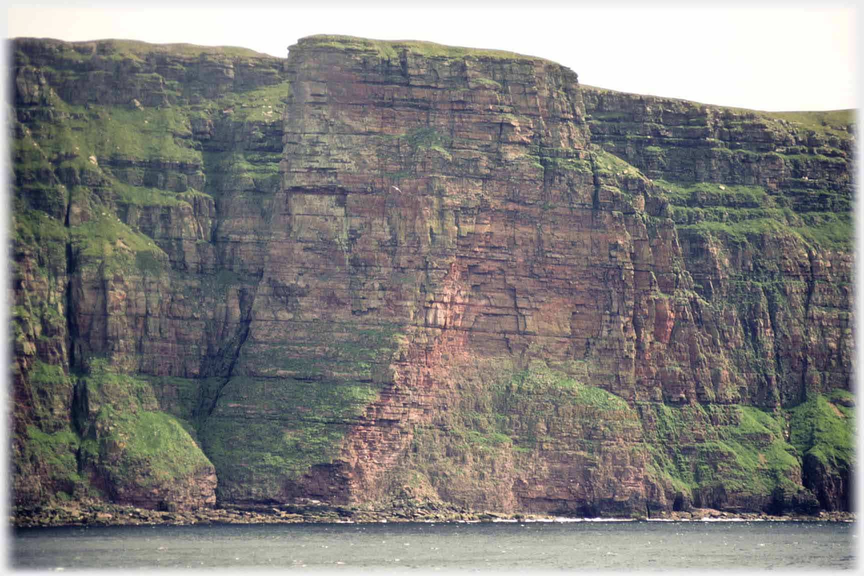 Massive bastion standing out from cliff face above sea.