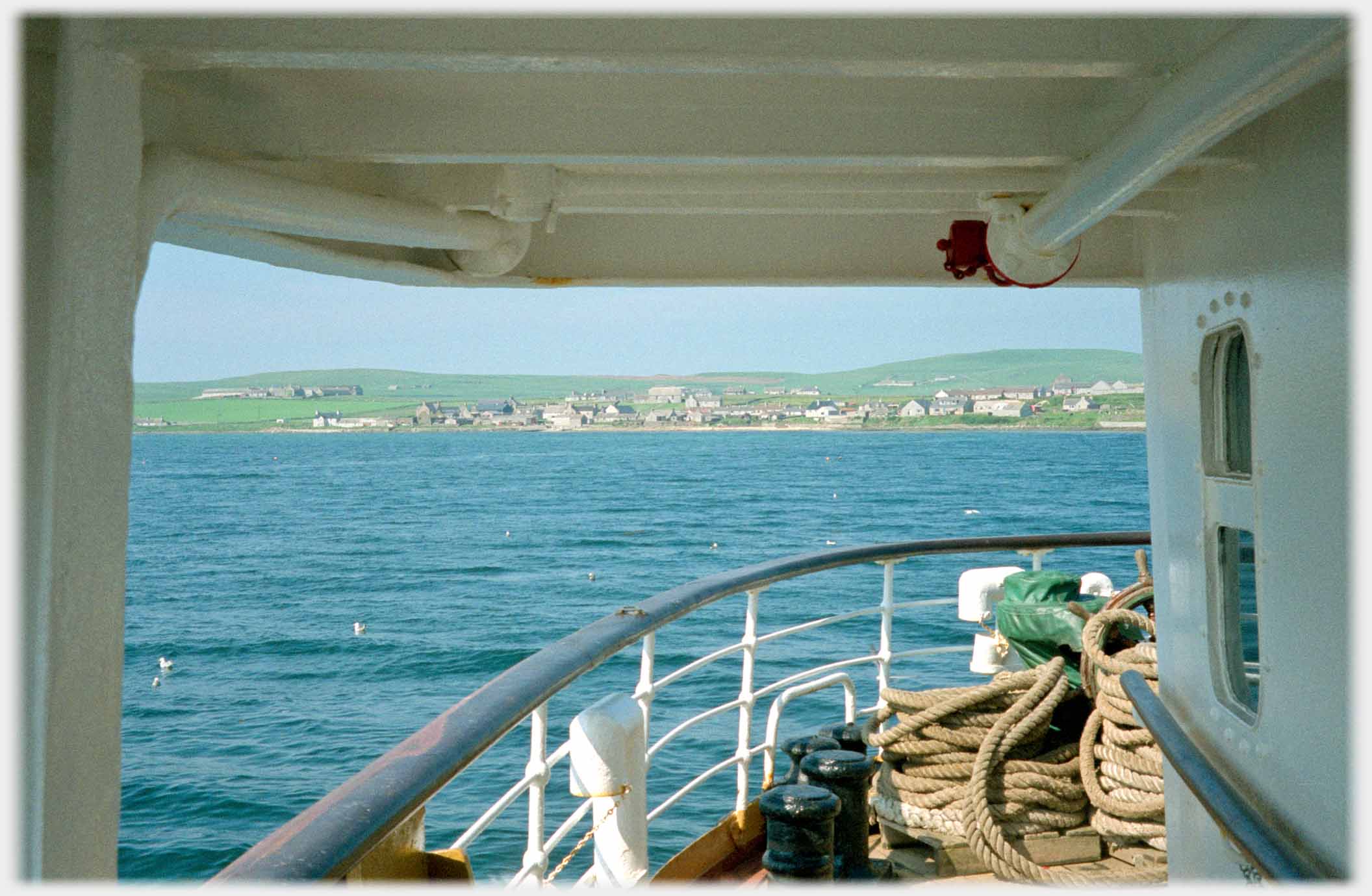 View from boat across sea to houses on land.