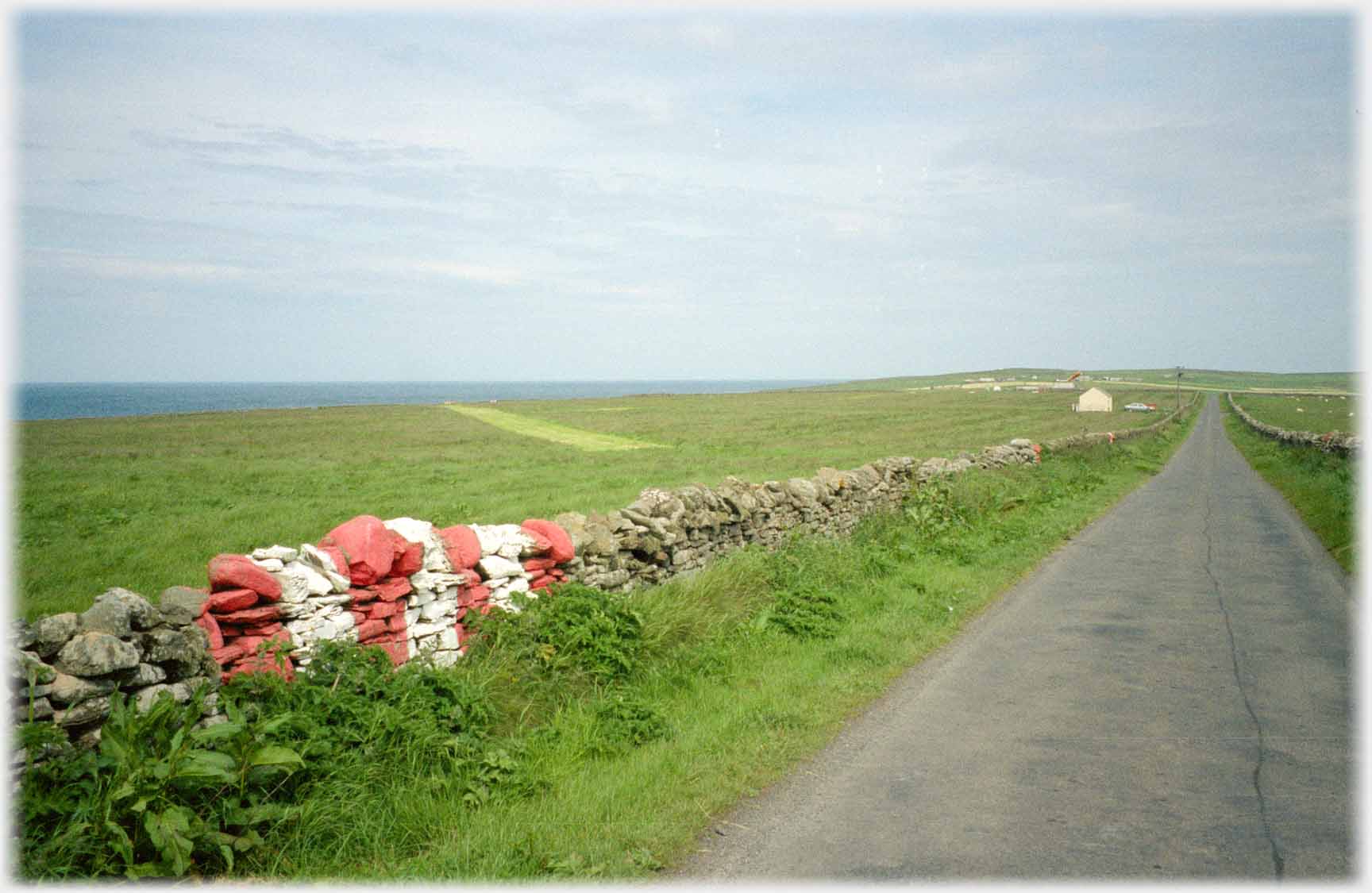Fields by road with red and white strips on dividing dyke.