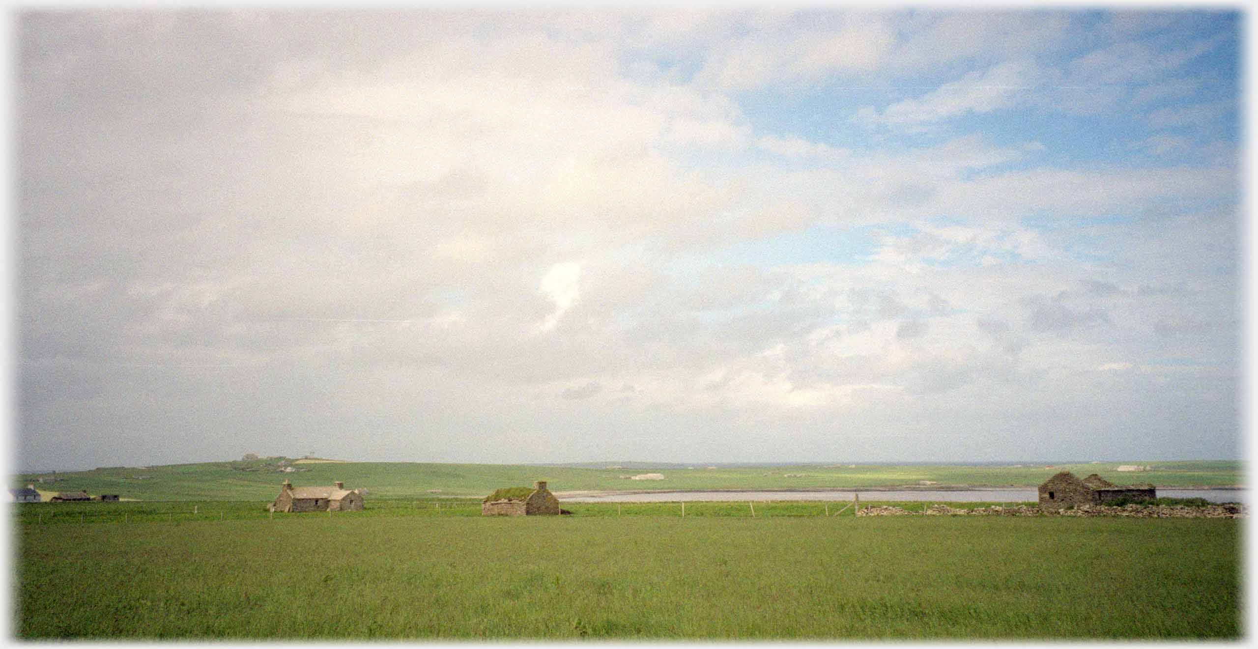 Dotted roofless houses under hig sky of soft clouds.