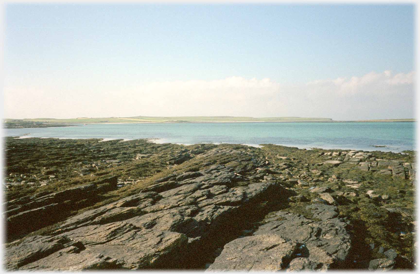 Flat shelving rocks running to blue-green sea.