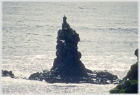 Black sea stack in reflecting water.