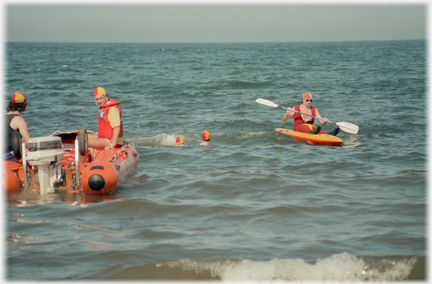 Two boats in sea with two heads in caps between them.