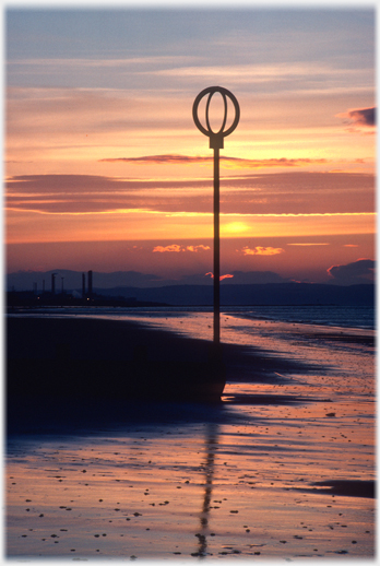 Groin warning marker with tide out and sun setting.