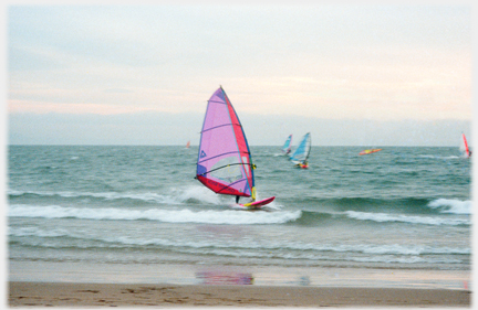 Wind-surfer running along the inshore waves.