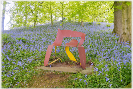Metal seat with bluebells as background .