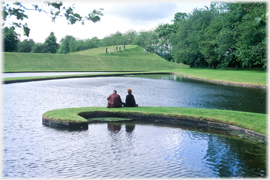 Two people sitting on the grass hook.