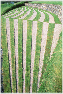 Tapering furrows meeting at line giving impression of angled ground.