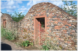 Undulating brick wall with door.