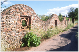 Undulating brick wall with window.