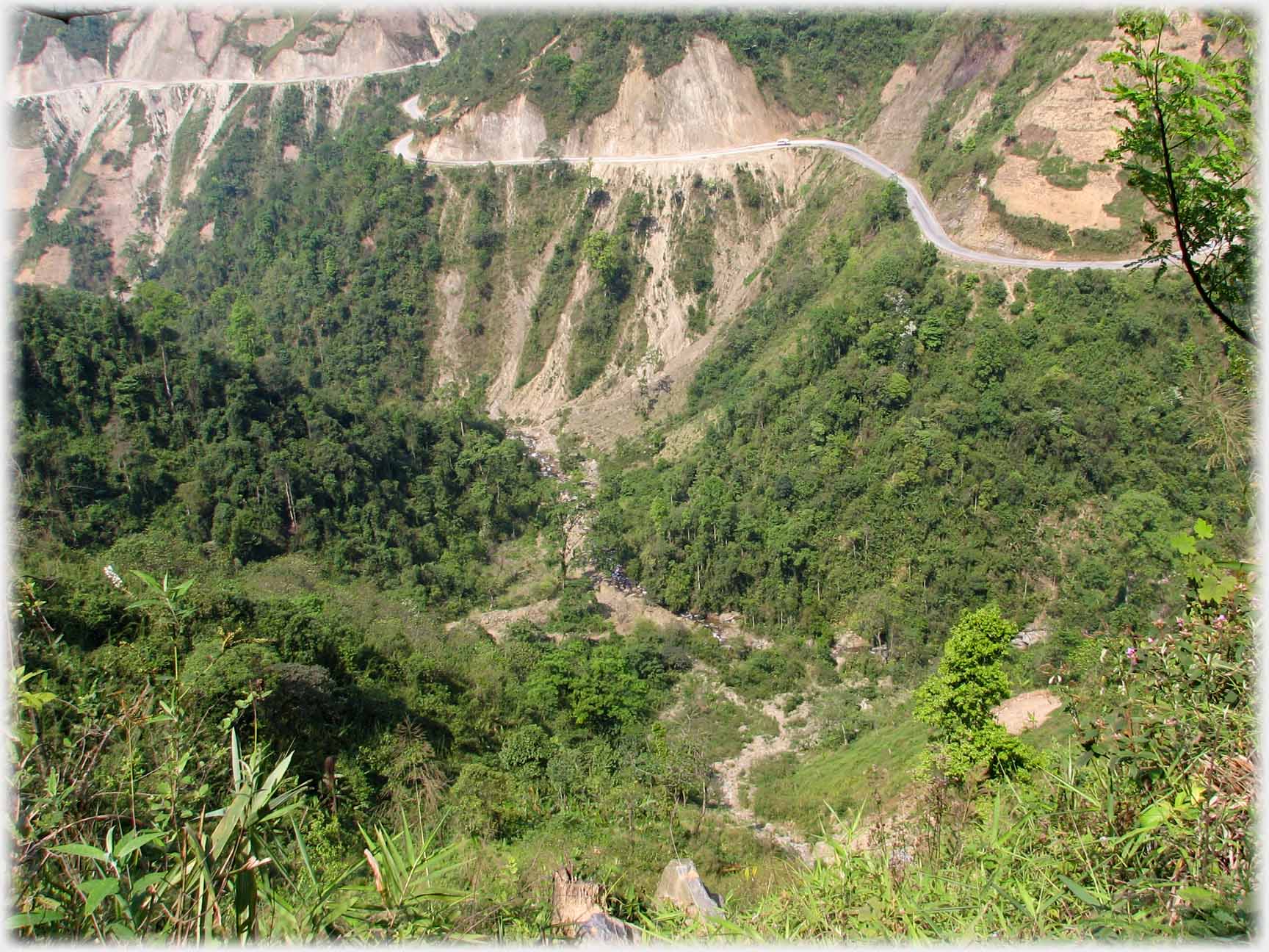 Road clinging to vertical hillside, vehicle just visible.