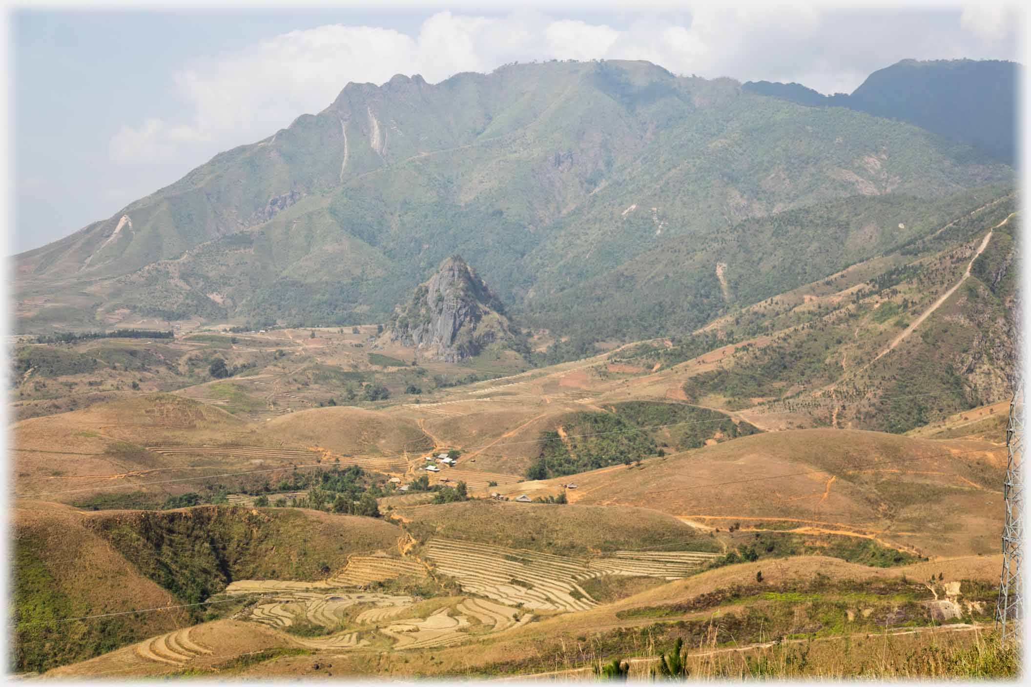 Valley with mountains beyond and single conical karst.