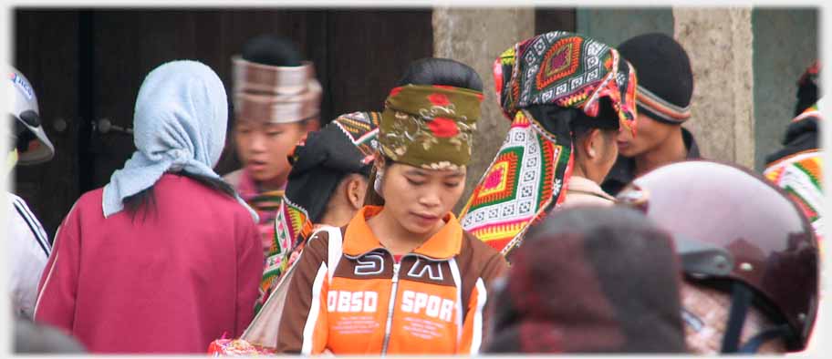 A range of heads in different coverings: helmet, scarf, top knot, cap, bronze bands.