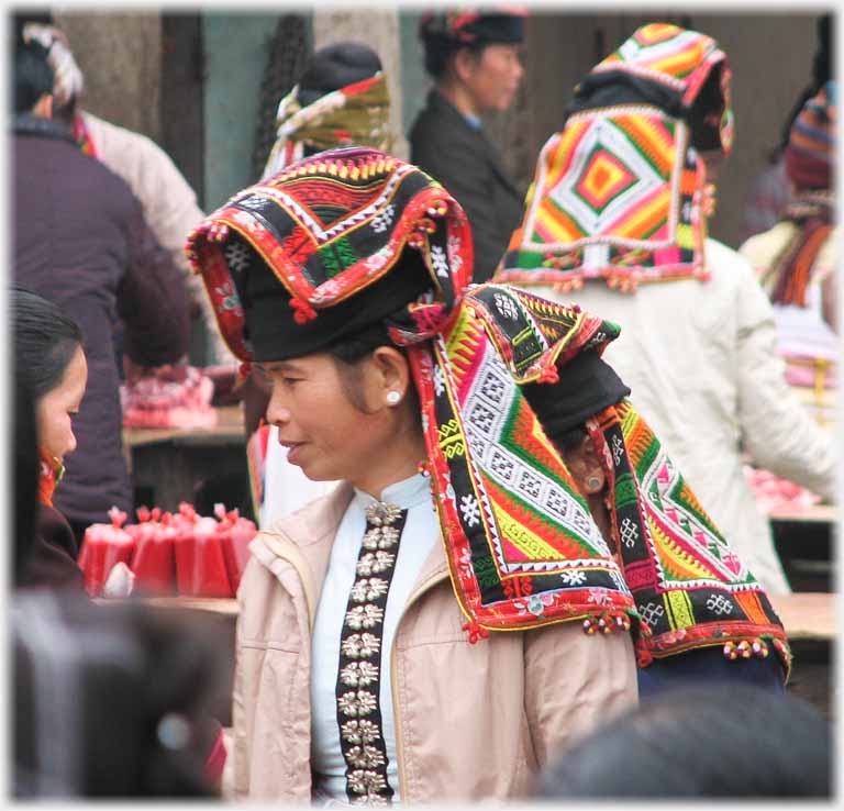 Younger woman elaborate headdress, and light coloured clothes.