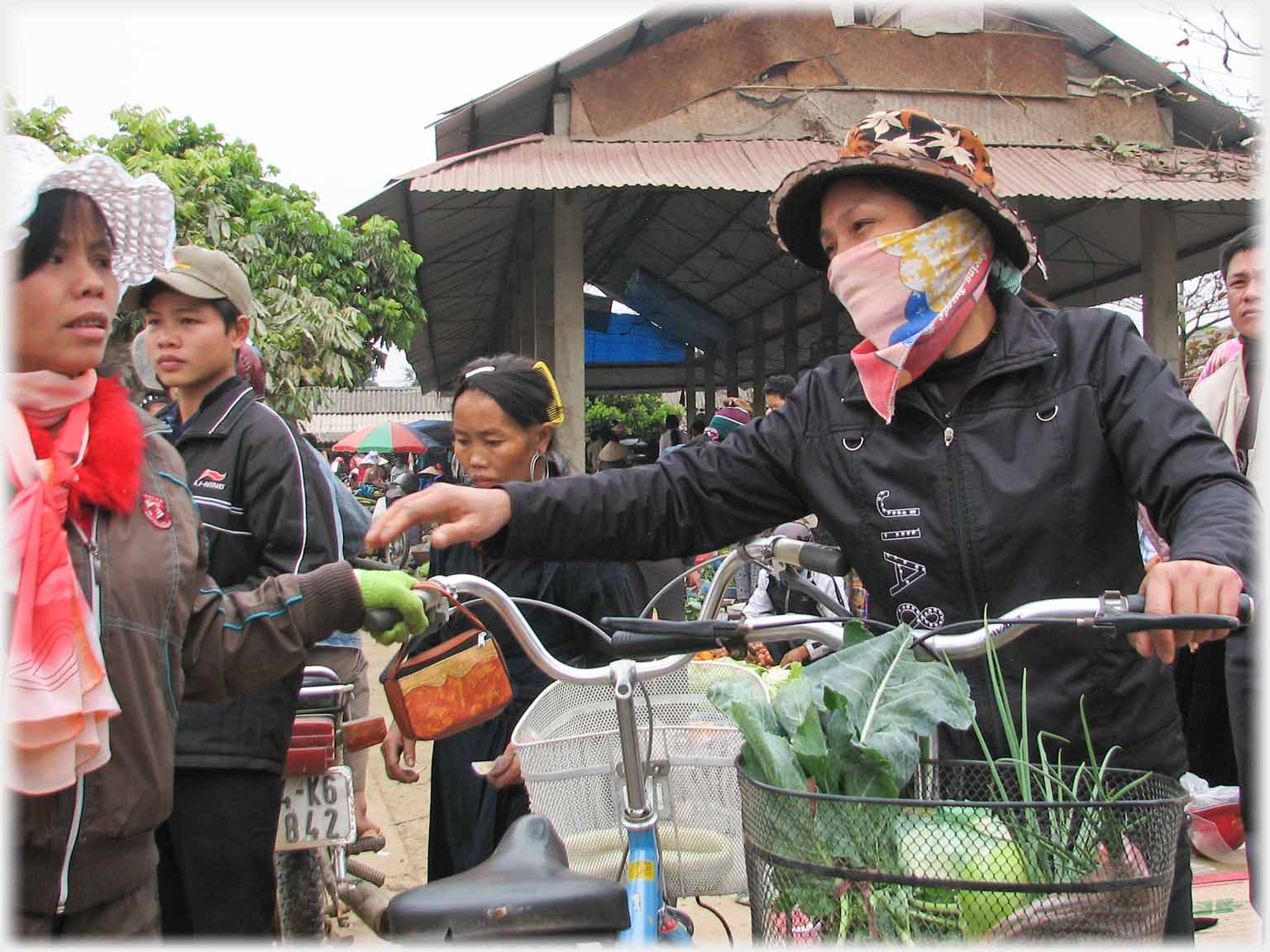 Two women with bicycles, loaded front basket on one.