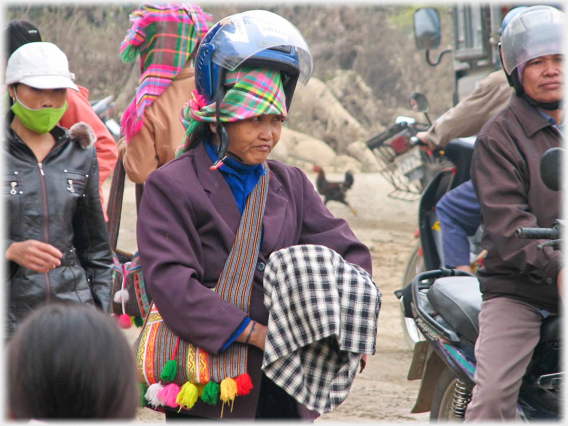 Woman looking quizzicle head scarf round top-knot and crash helmet perched above that - far from her face.