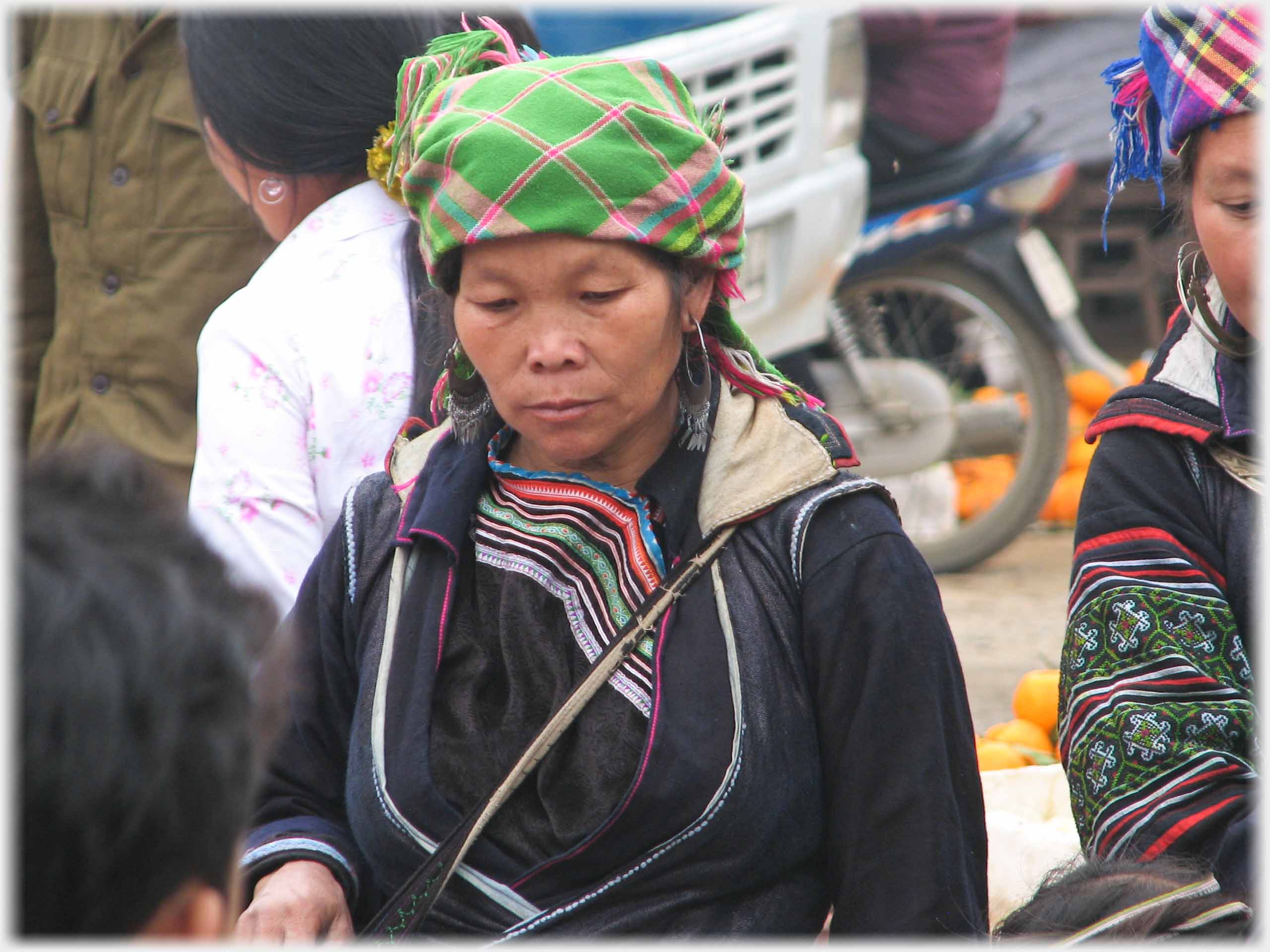 Woman in black with coloured head scarf.