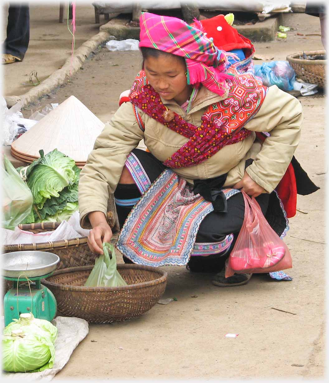 Woman squatting down examining vegetables.