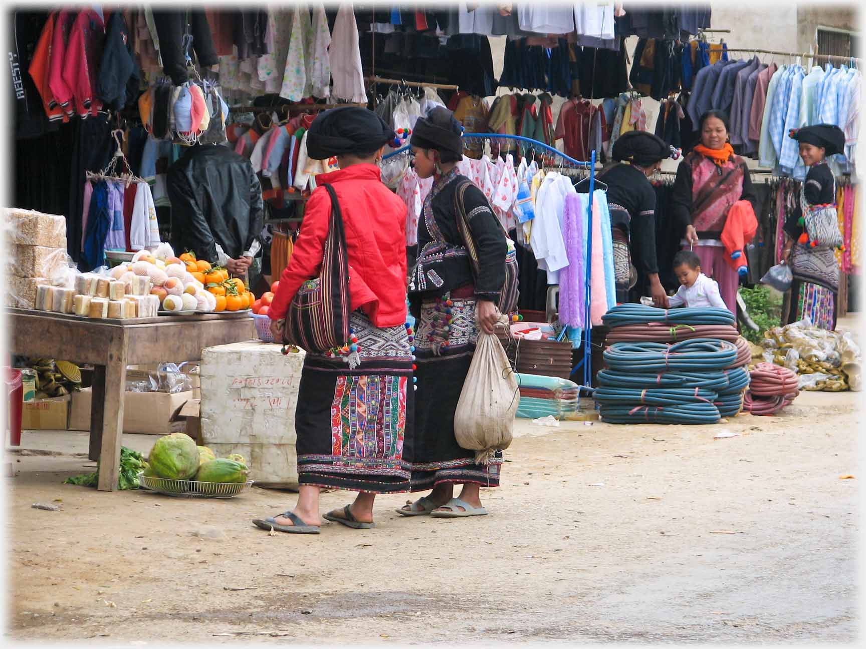 Two women at stall, in black, but one with bright orange padded jacket.