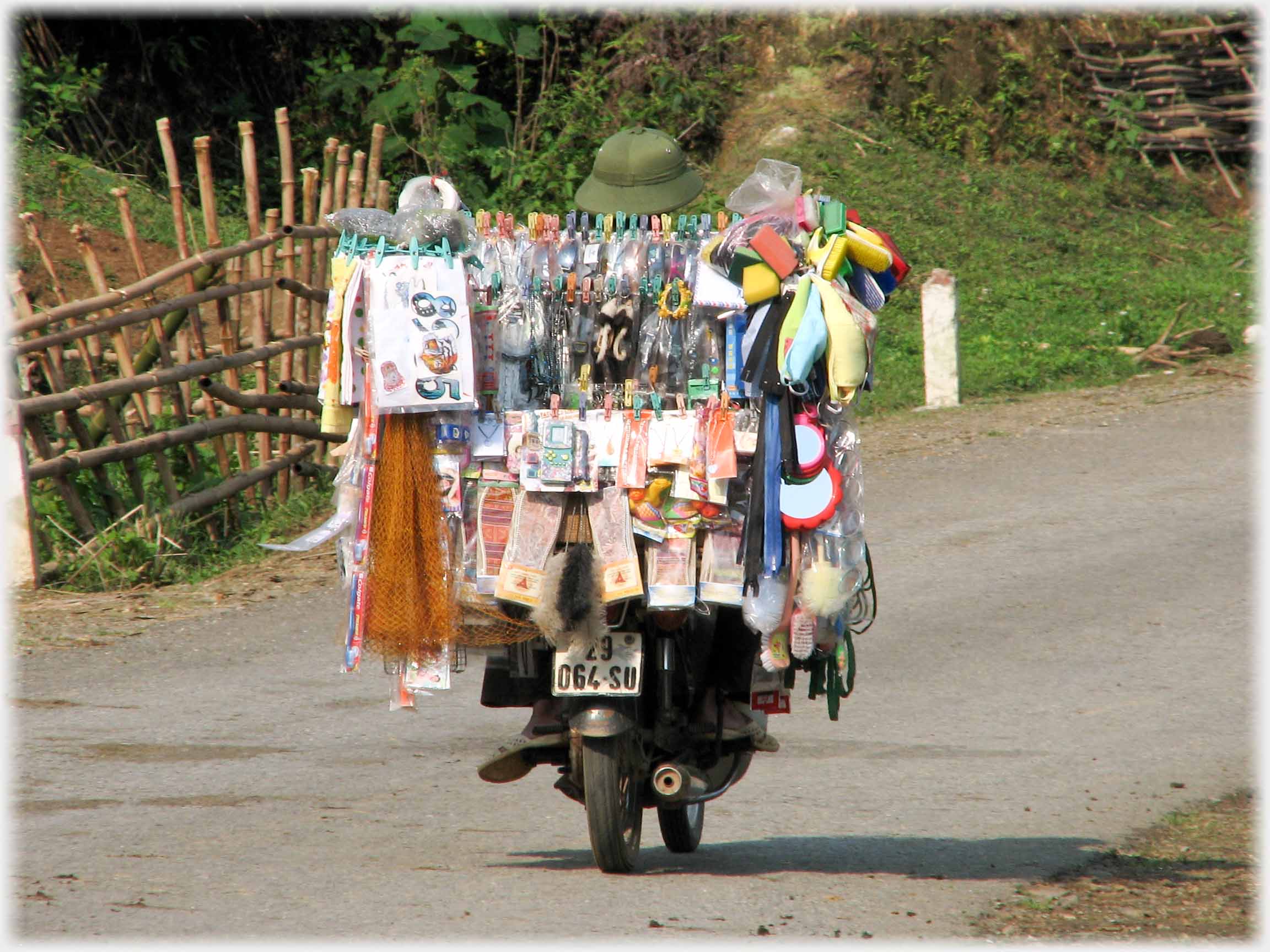 Rear view of motorbike with very large display of goods obscuring all but back wheel.