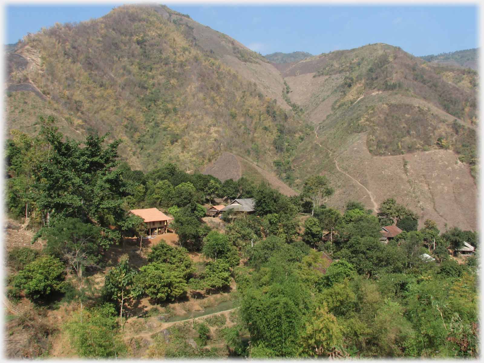 Village nestling in trees at foot of hills.