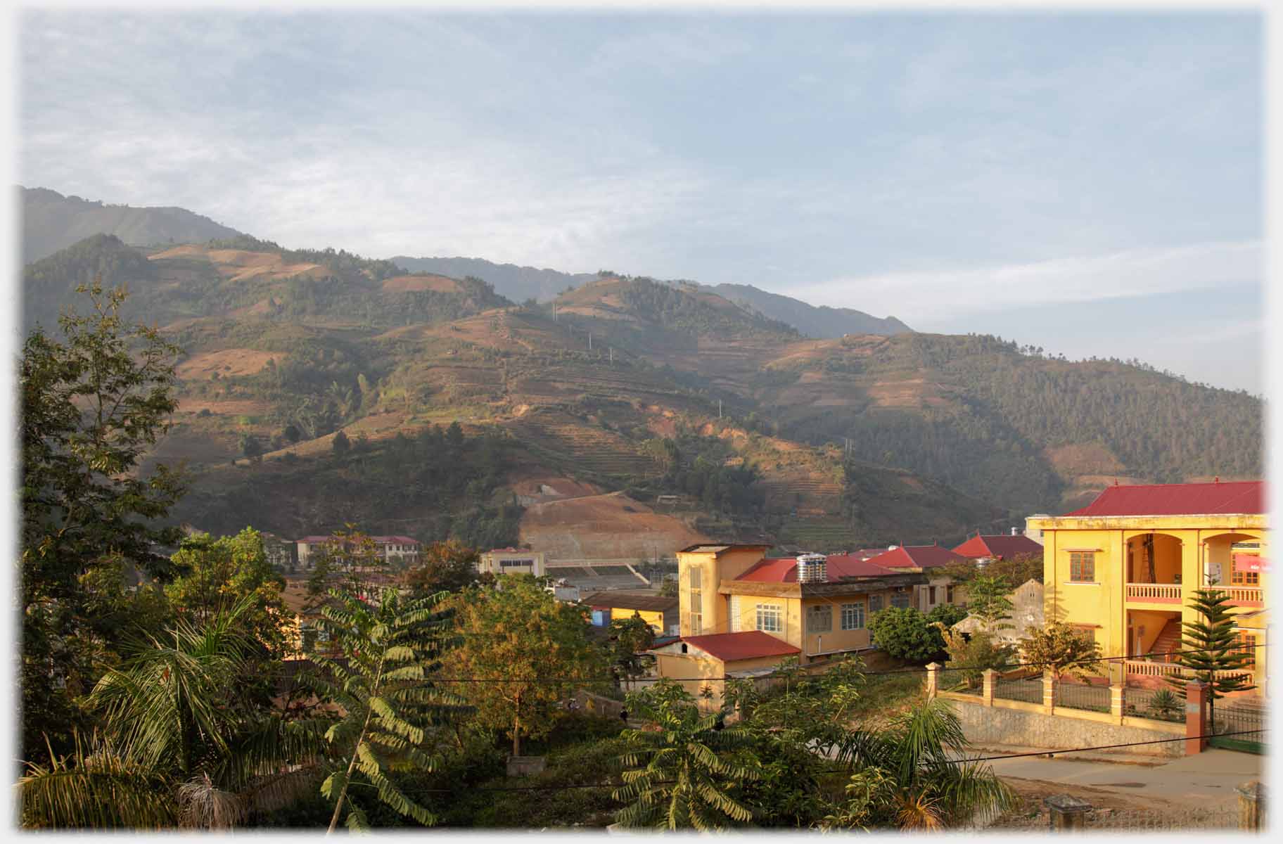 Ochre buildings, town beyond, hills beyond town.