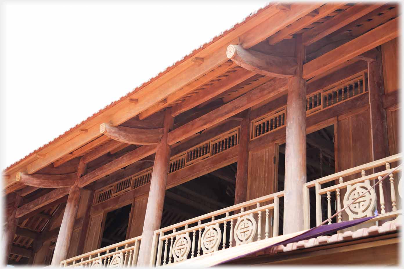 Looking upwards at the balcony and roof supports of a house under construction.