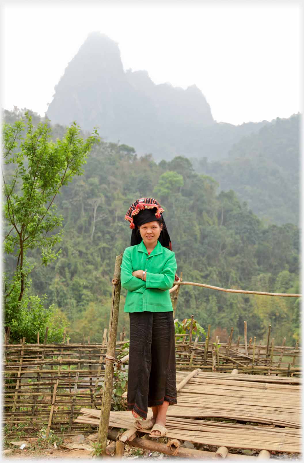 Same woman in green top with high karst mountain behind.