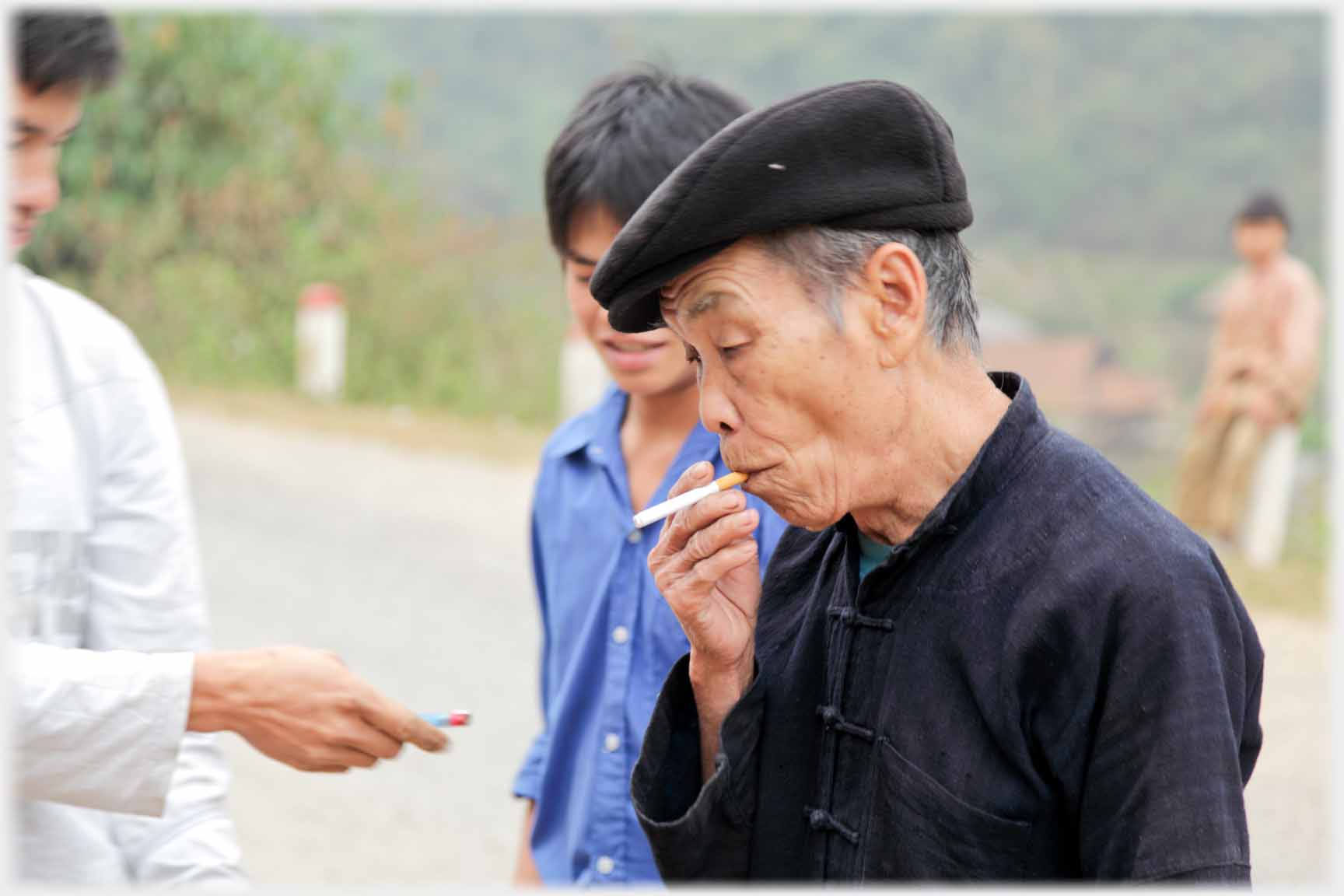 Older man with cigarette, lighter being proffered.