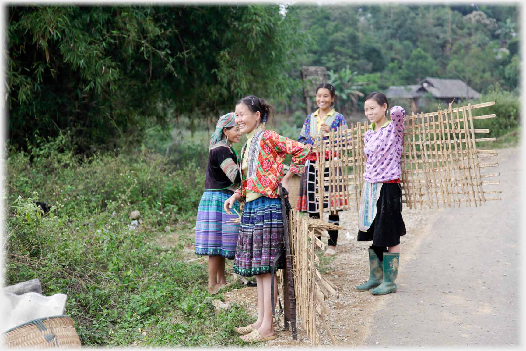 Four women holding wattle fencing.