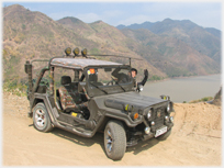 Jeep parked with hills and resevoir beyond.