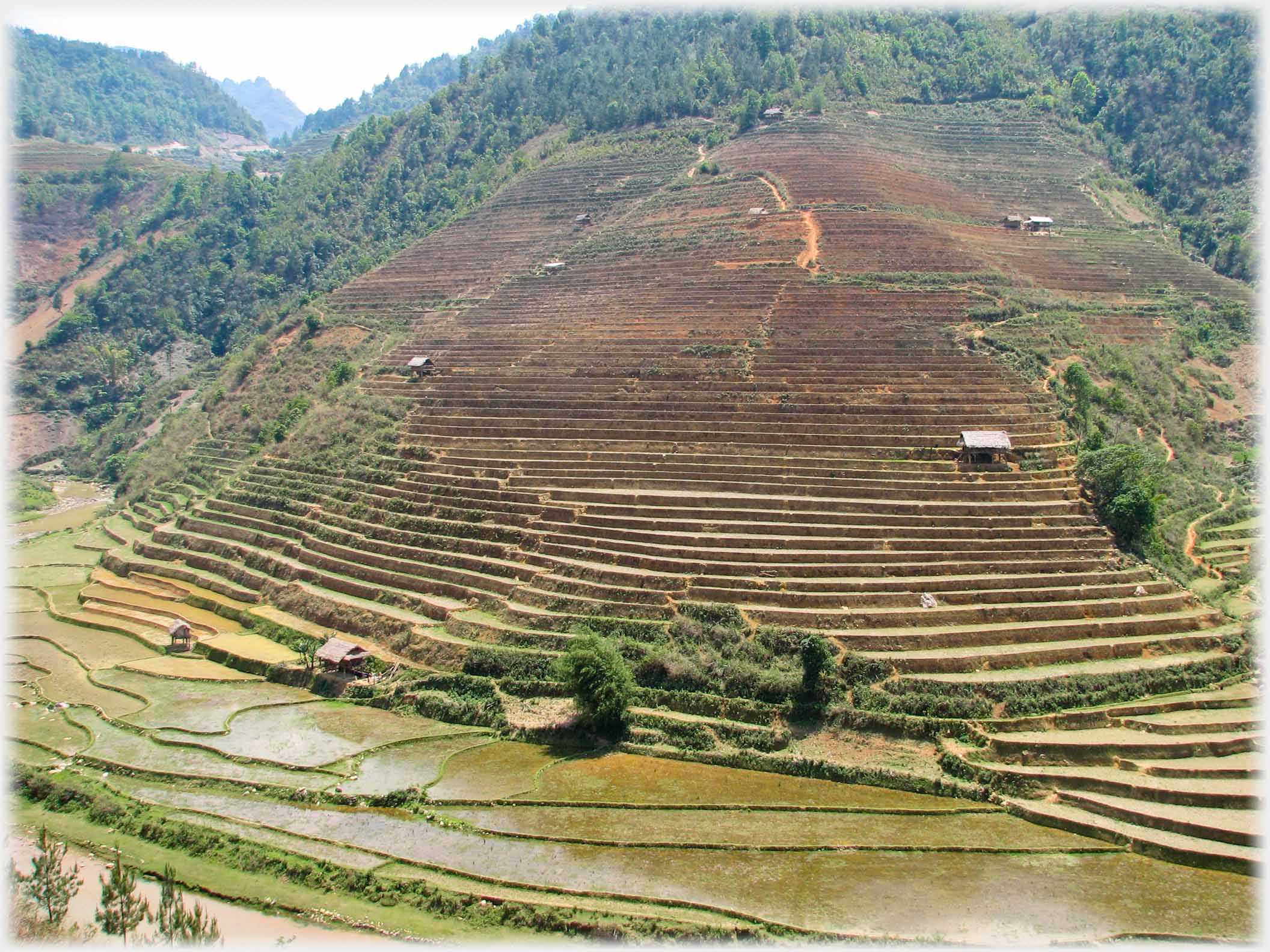 Terraces running down to flatter land and fields at their base.