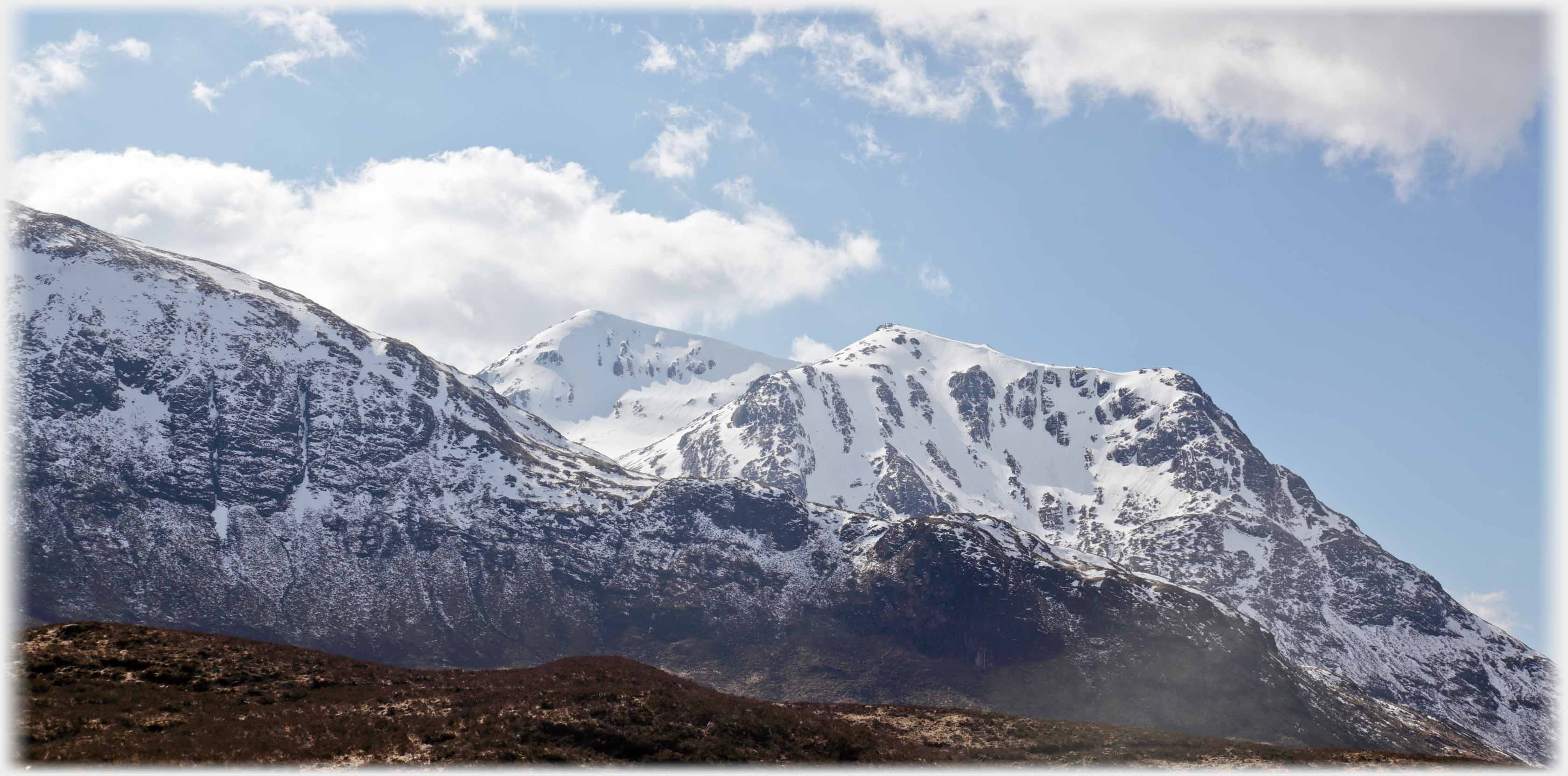 Sun catching snow on ridge of hills.